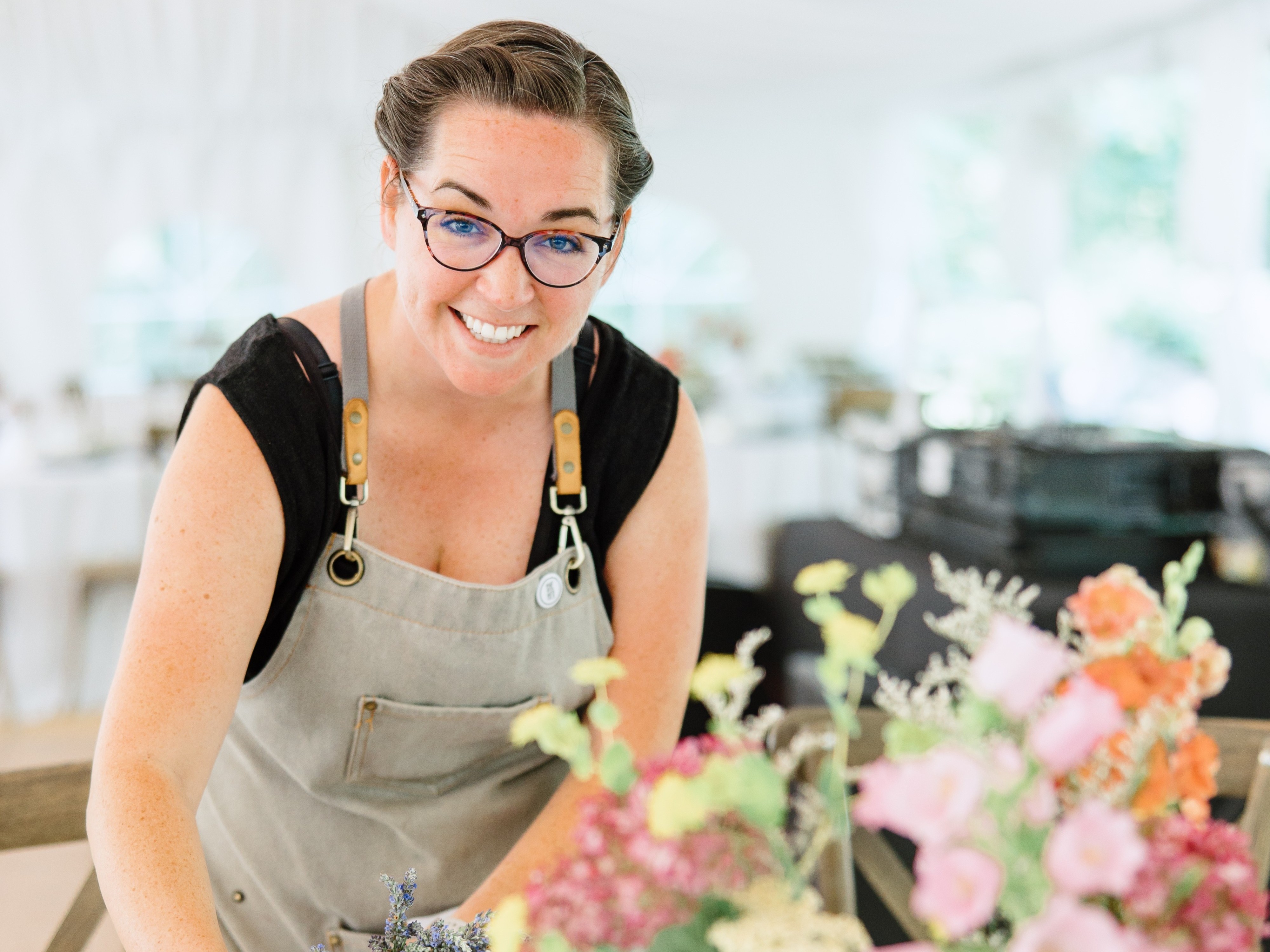 Mary, owner, smiling at camera, flowers in foreground