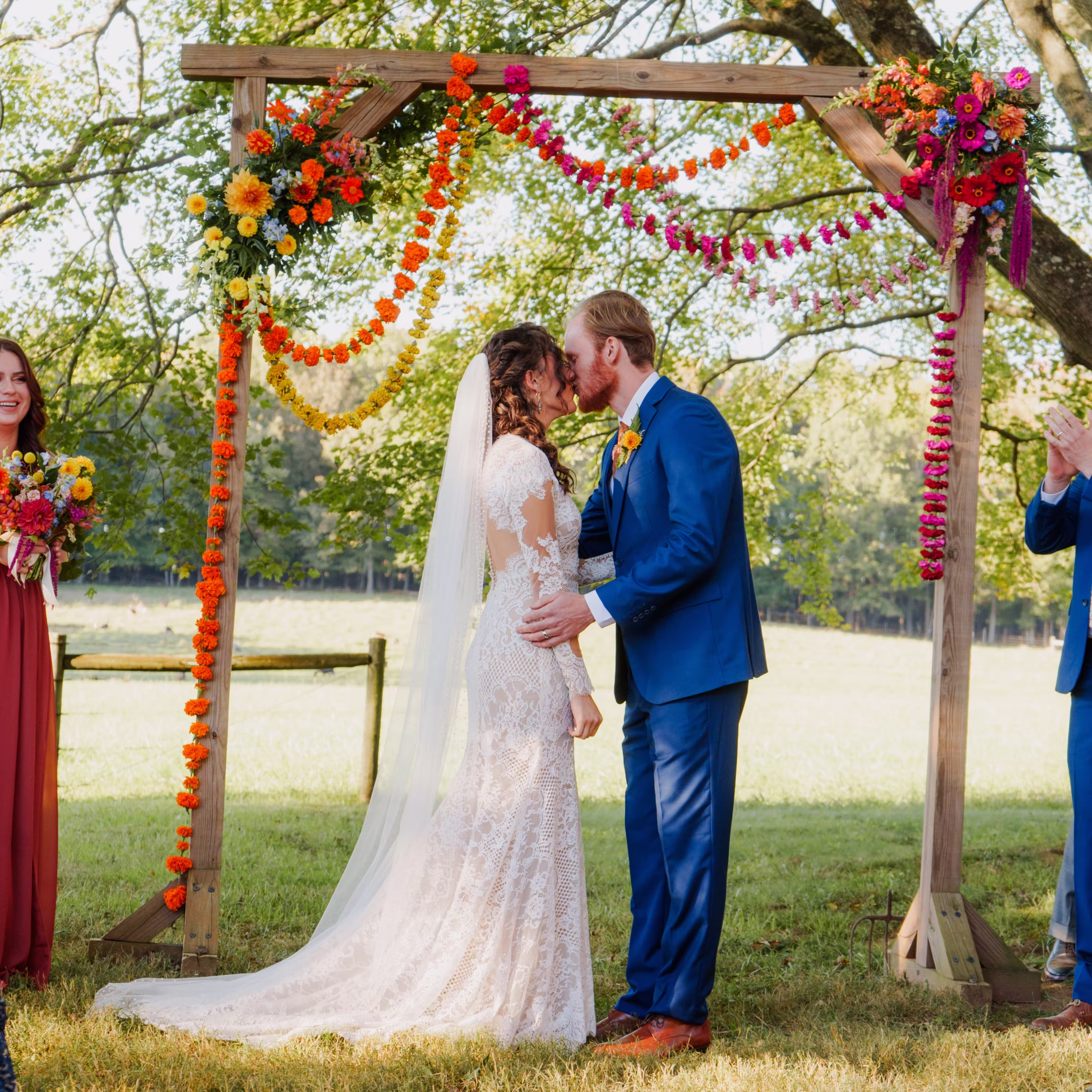 Couple kiss in front of a colorful arbor